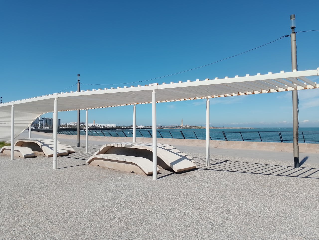View of modern seaside promenade with benches and pergola in Casablanca, ideal for relaxation.